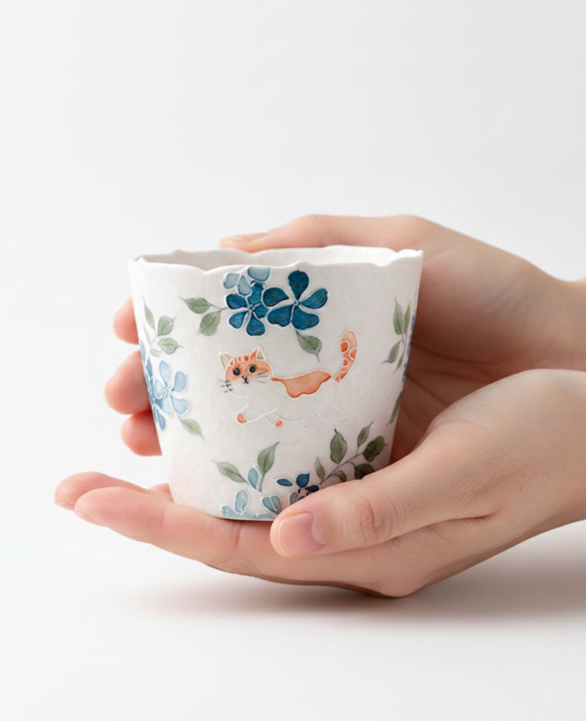 whisker trail hand painted porcelain cup for coffee and tea with blue floral and cute cat pattern held in hands for display
